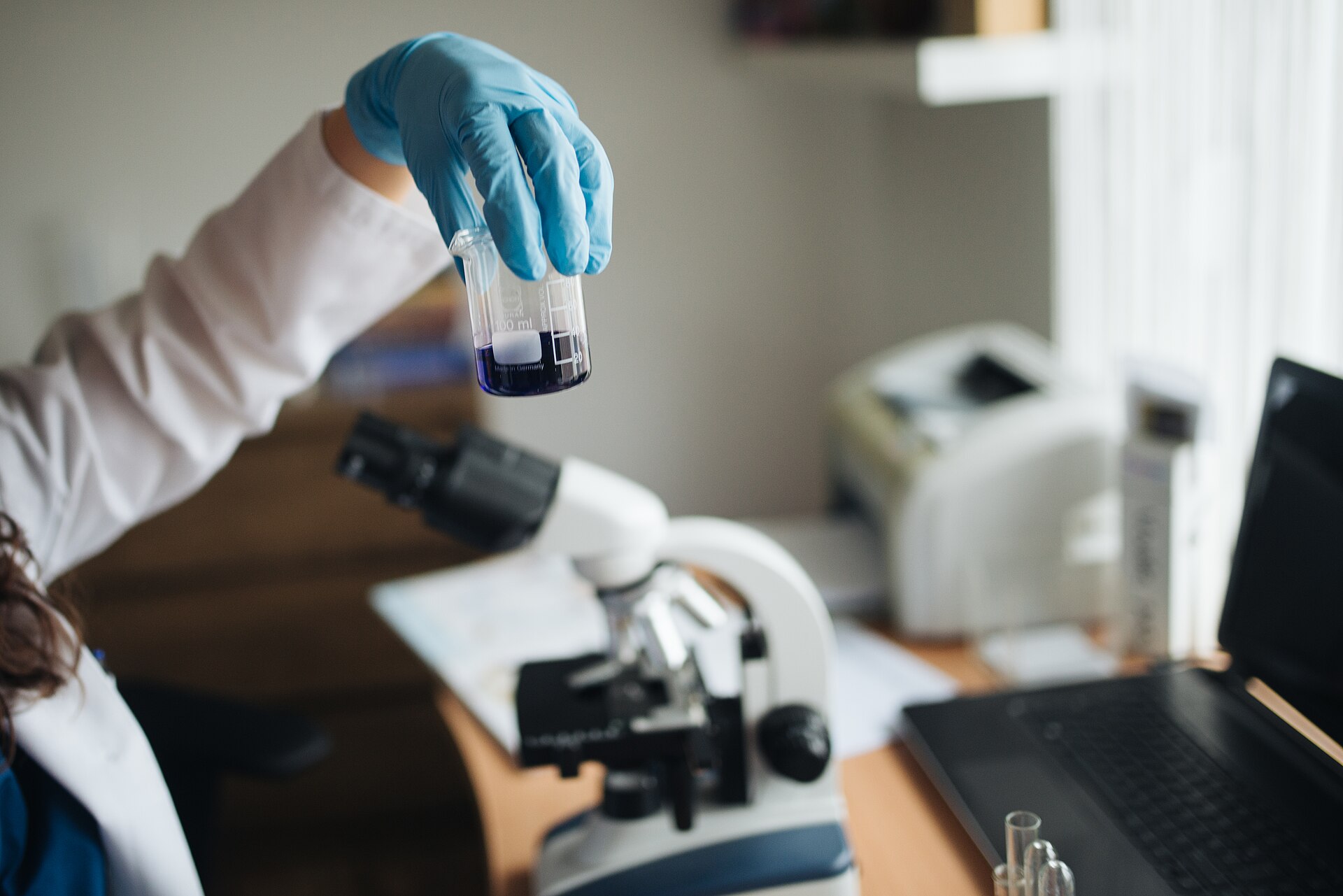 Close-up of a laboratory technician examining a chemical reaction in a glass beaker.