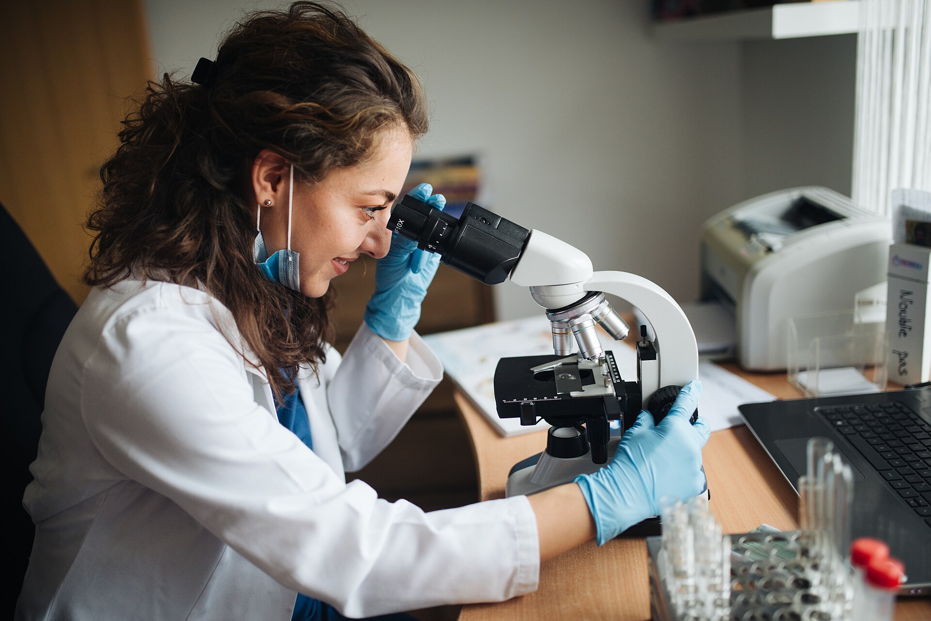 Laboratory technician adjusting a microscope while examining a slide.